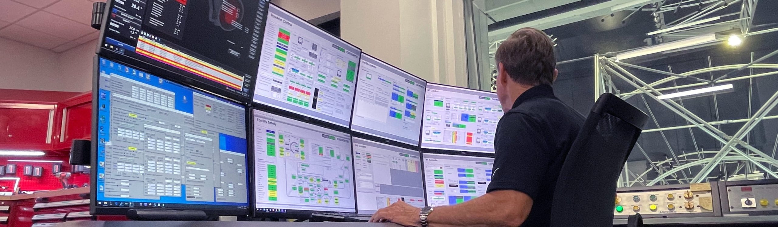 Man sitting in front of computer with eight screens